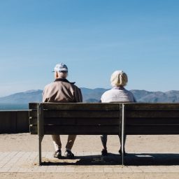 Older couple sitting together on a bench.