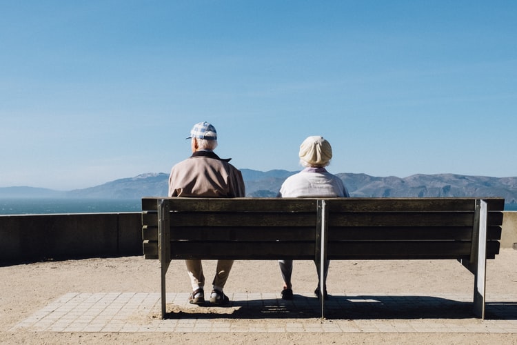 Older couple sitting together on a bench.