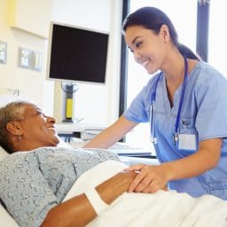 Nurse chats with patient in hospital room.