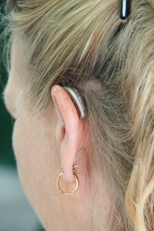 A close-up of a woman with a hearing aid.