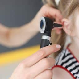 Doctor examines ear drum of little girl. Hearing impairment in children concept