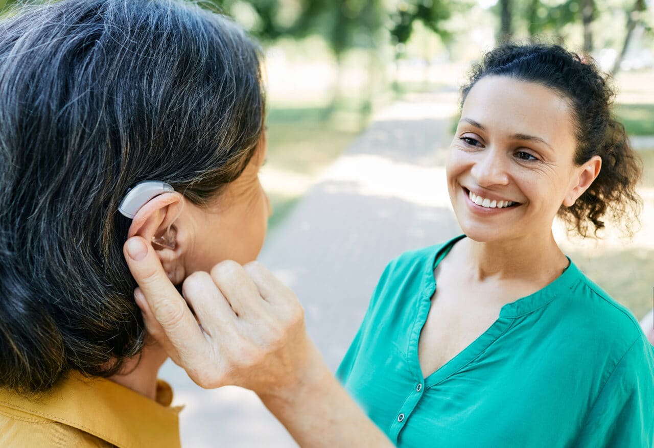 Woman with hearing aid chats with her friend.