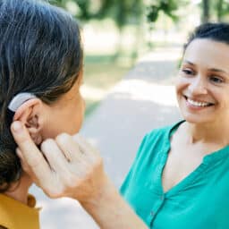 Woman with hearing aid chats with her friend.