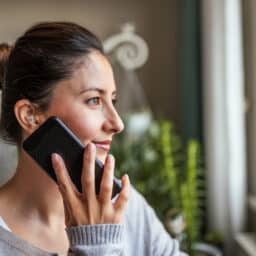 Woman wearing a hearing aid holder a phone next to her ear