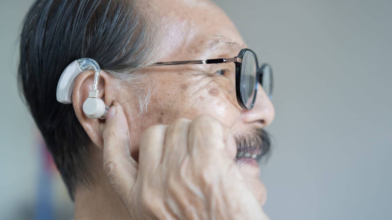 Man holds hand to hearing aid