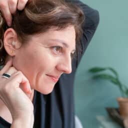 Woman smiles after placing hearing aid
