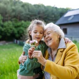 Grandma looking at a flower with her granddaughter