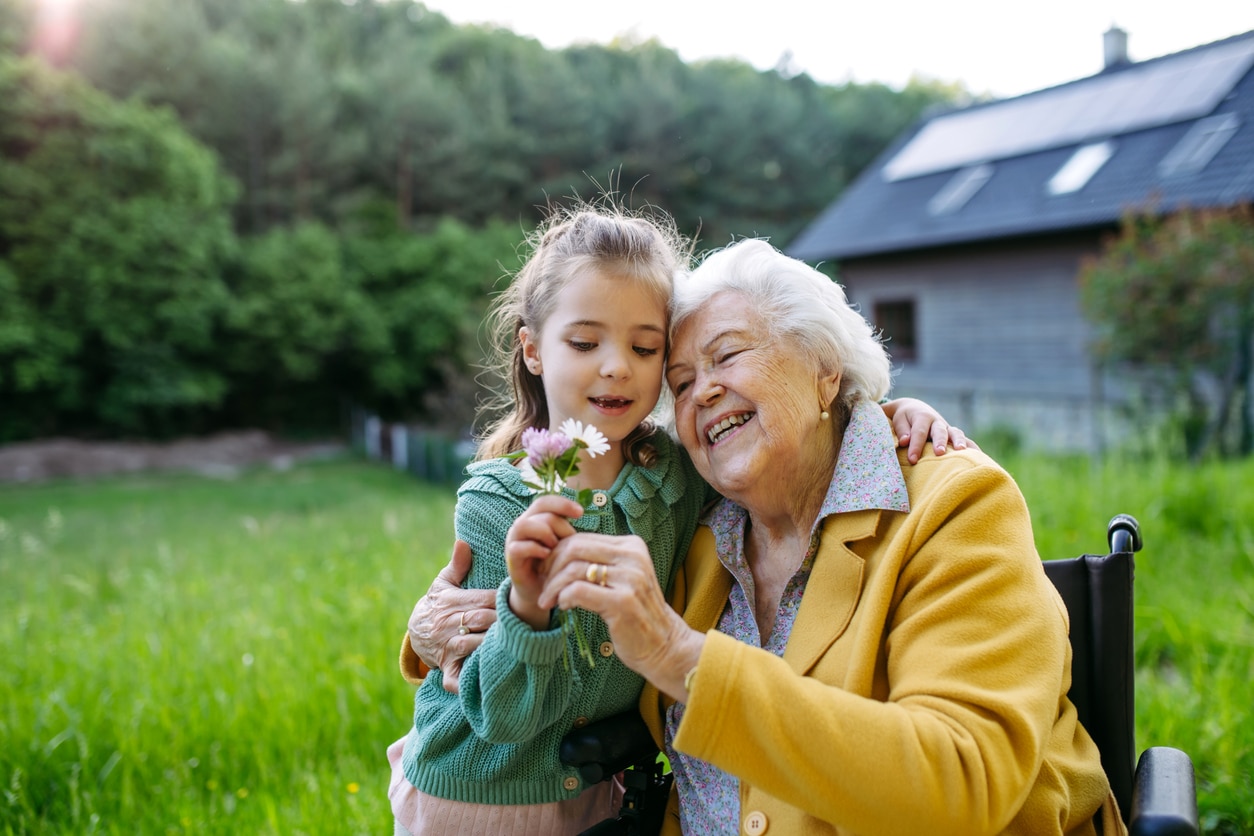 Grandma looking at a flower with her granddaughter.