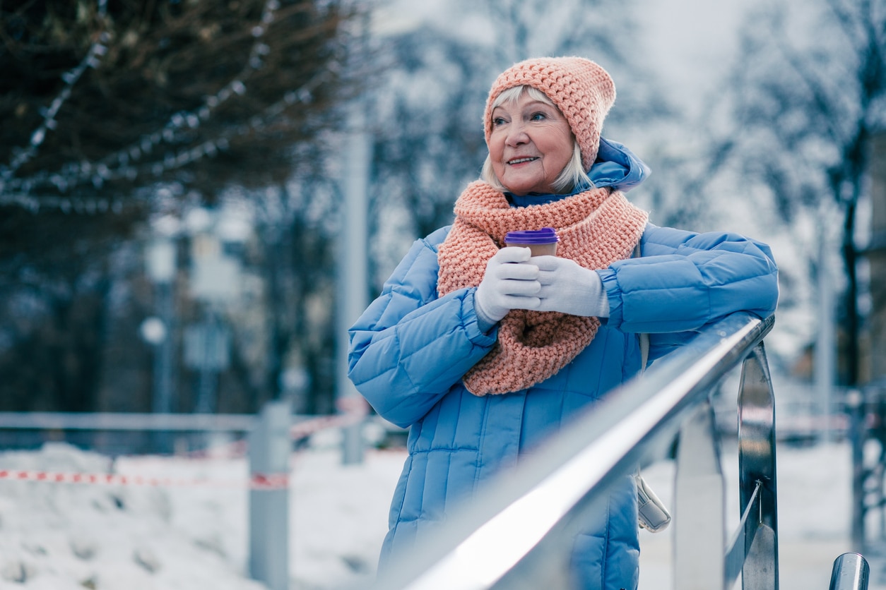 Senior woman drinking a coffee in the snowy outdoors.