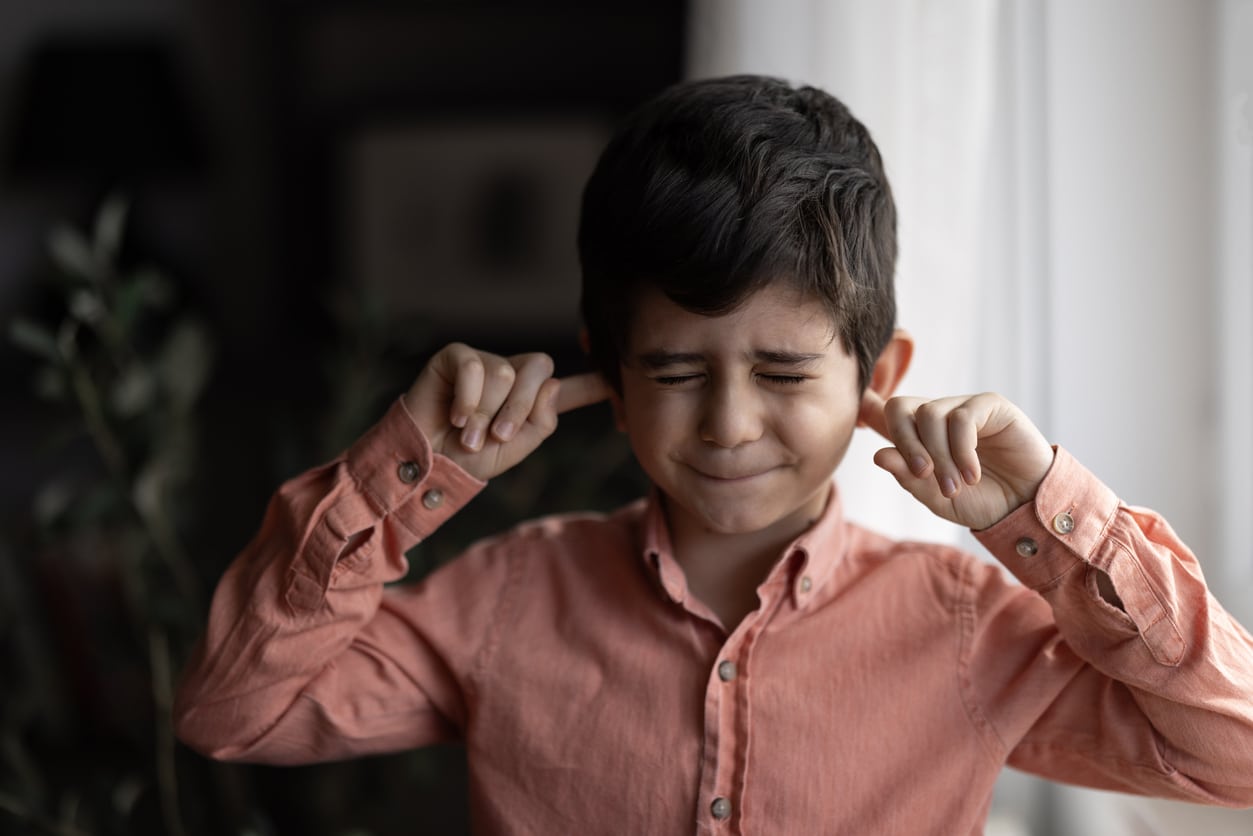 Child putting his fingers in his ears.