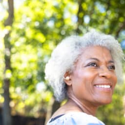 Senior woman smiling while showing off her hearing aid